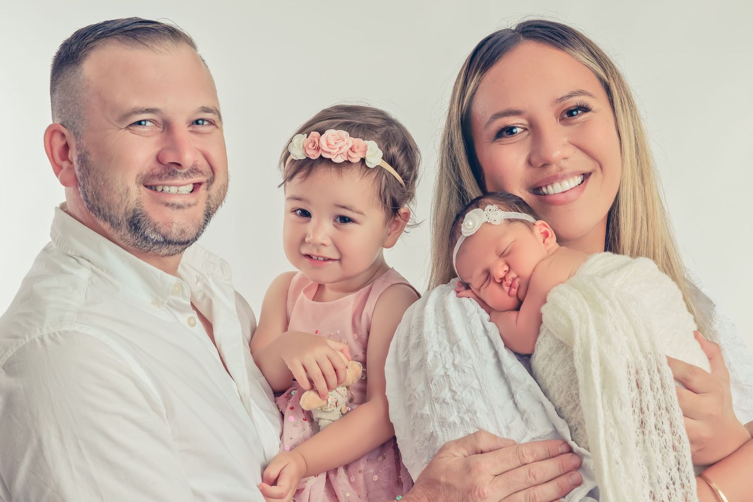 A series of connected portrait photos showing a happy family with a baby in white outfits against a light background.