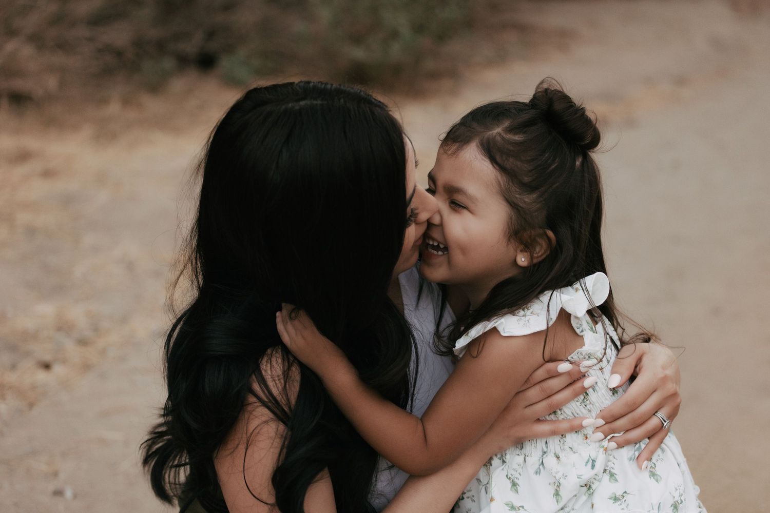 Tender moment captured between parent and child embracing outdoors on dirt path.