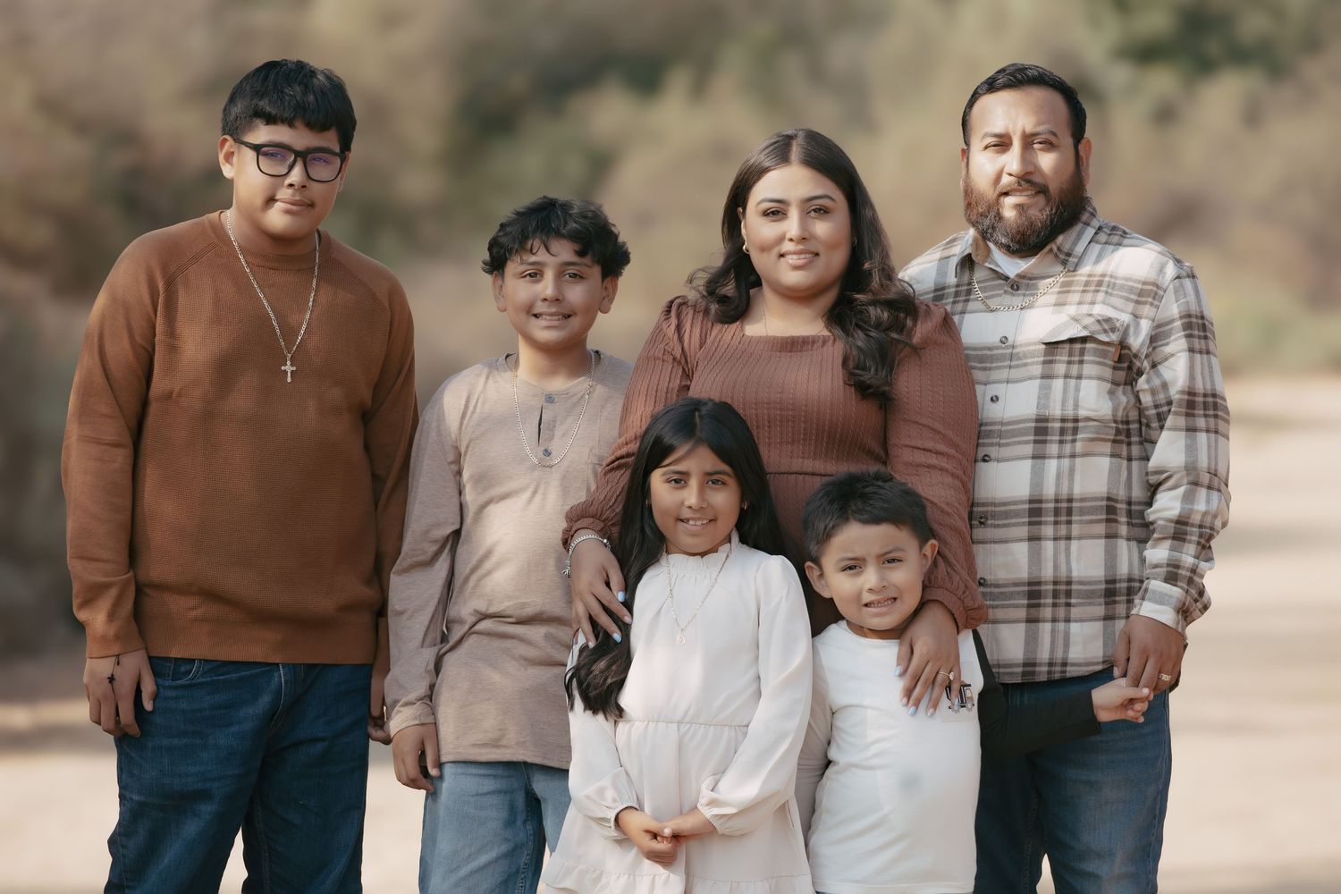 Multi-generational family of six poses together for outdoor portrait in casual autumn attire.