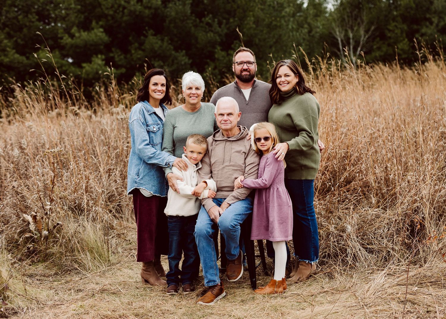 A series of outdoor family portrait shots taken in a field with tall golden grass during sunset.