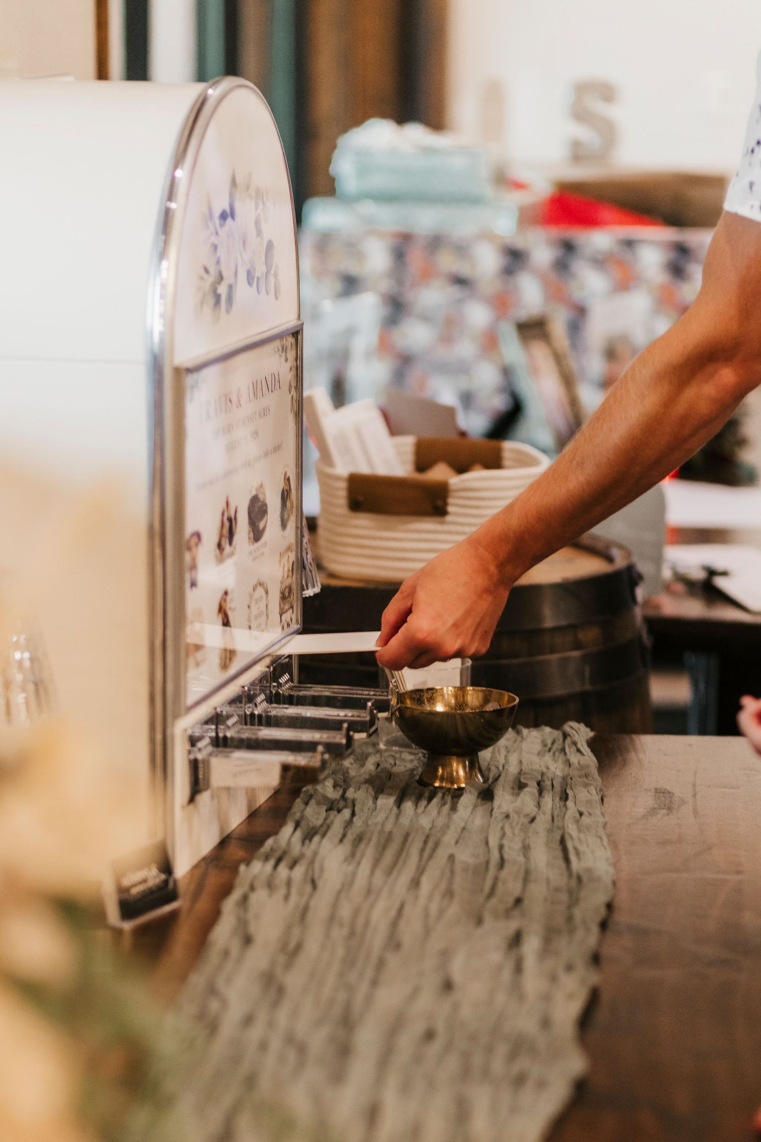 A person's hand placing a small brass bowl on a rustic wooden counter at a market stall.