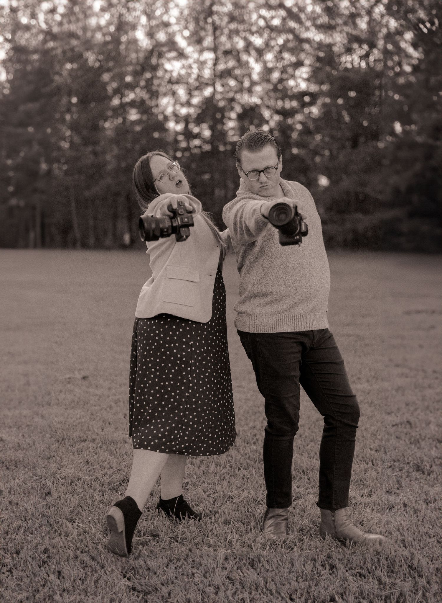 Husband and wife wedding photographers laughing together outside