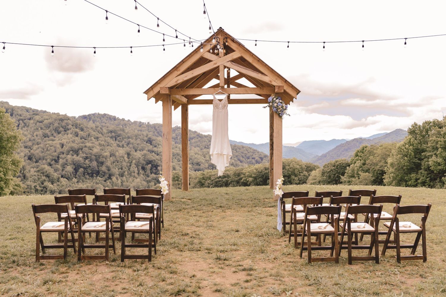 Wedding dress hanging from the ceremony arbor at The Heavens Venue in Hot Springs, NC