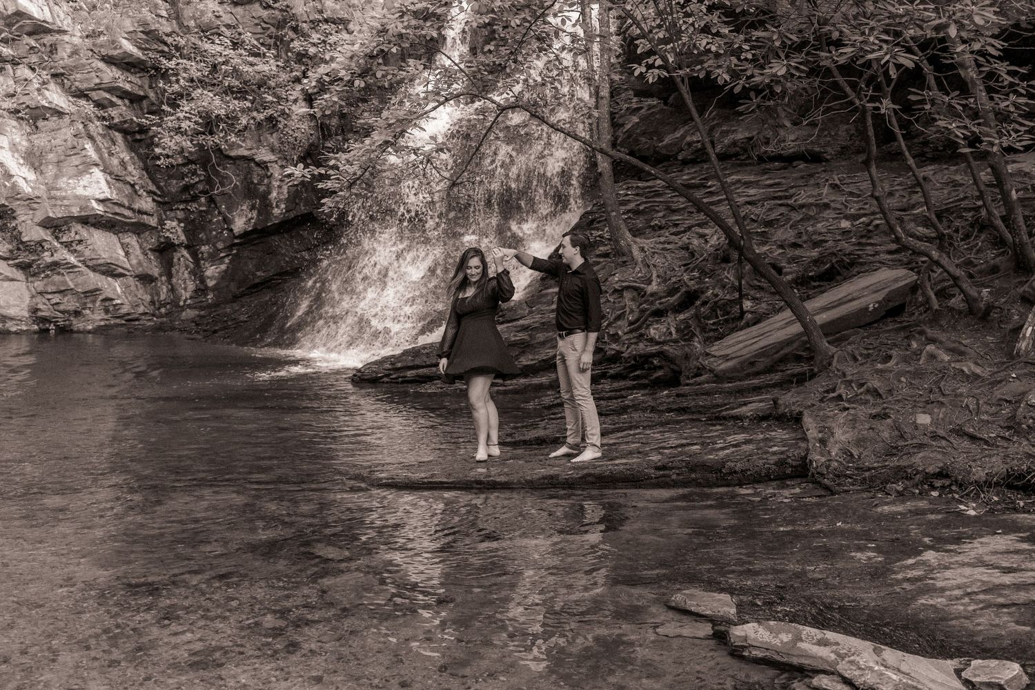 Engaged couple dancing in front of a waterfall at Hanging Rock State Park in Danbury, NC