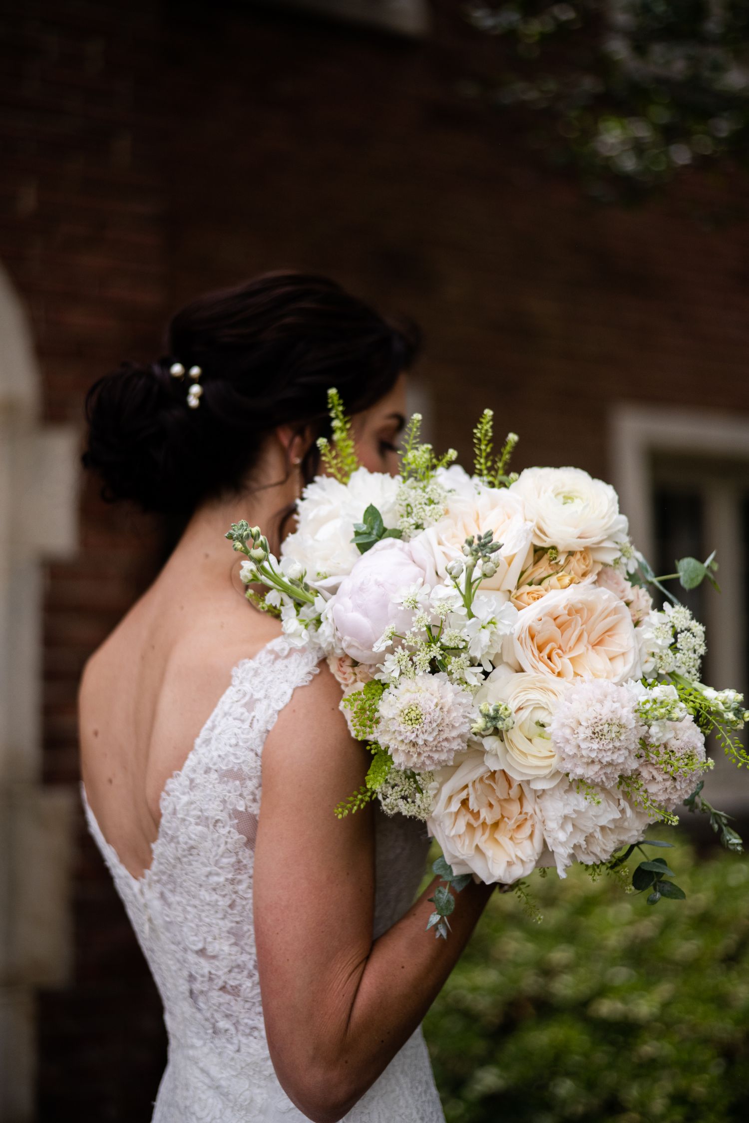Elegant white bridal bouquet with roses and delicate lace detail on wedding dress.