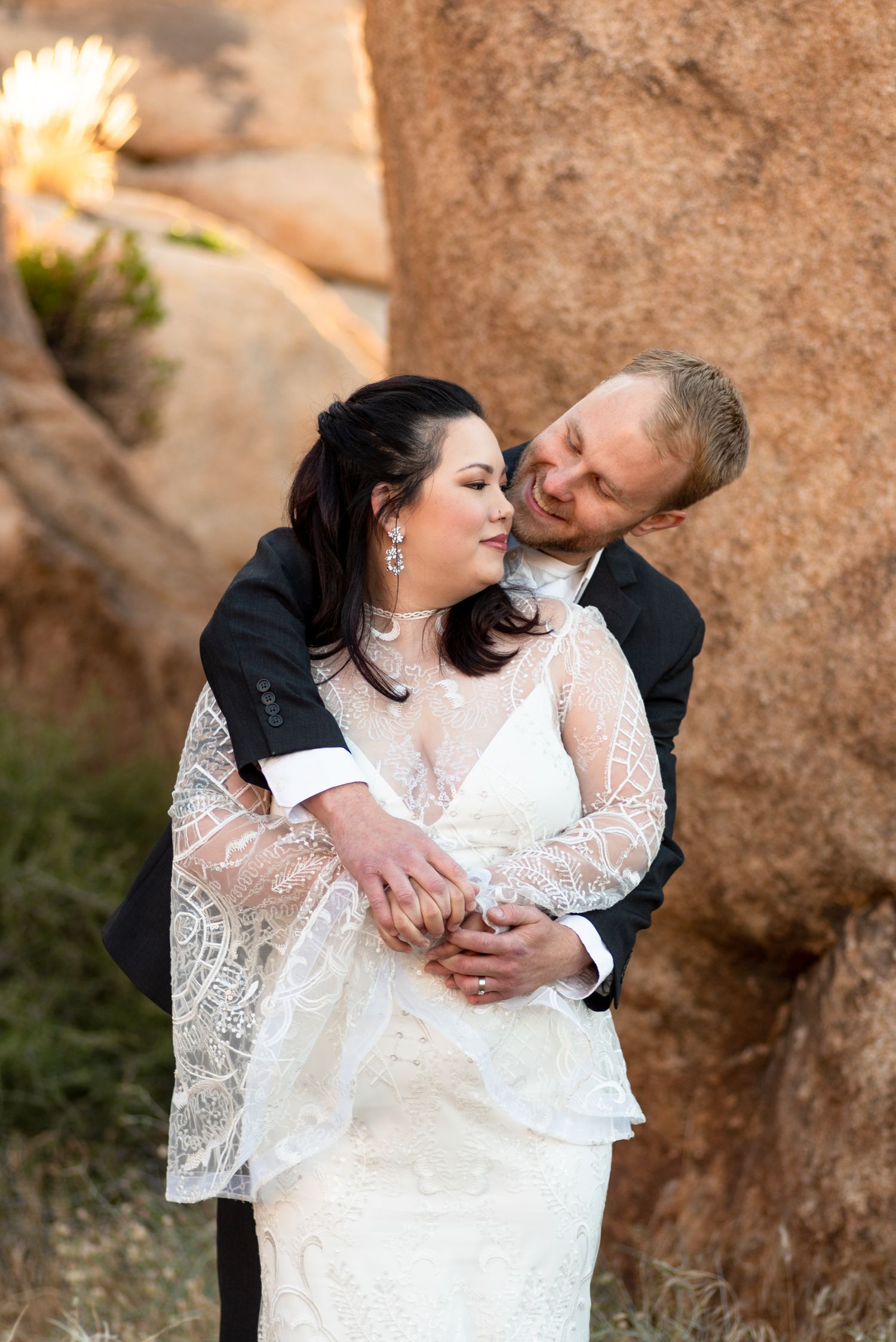 An intimate wedding portrait against desert rocks at Joshua Tree National Park at sunrise.