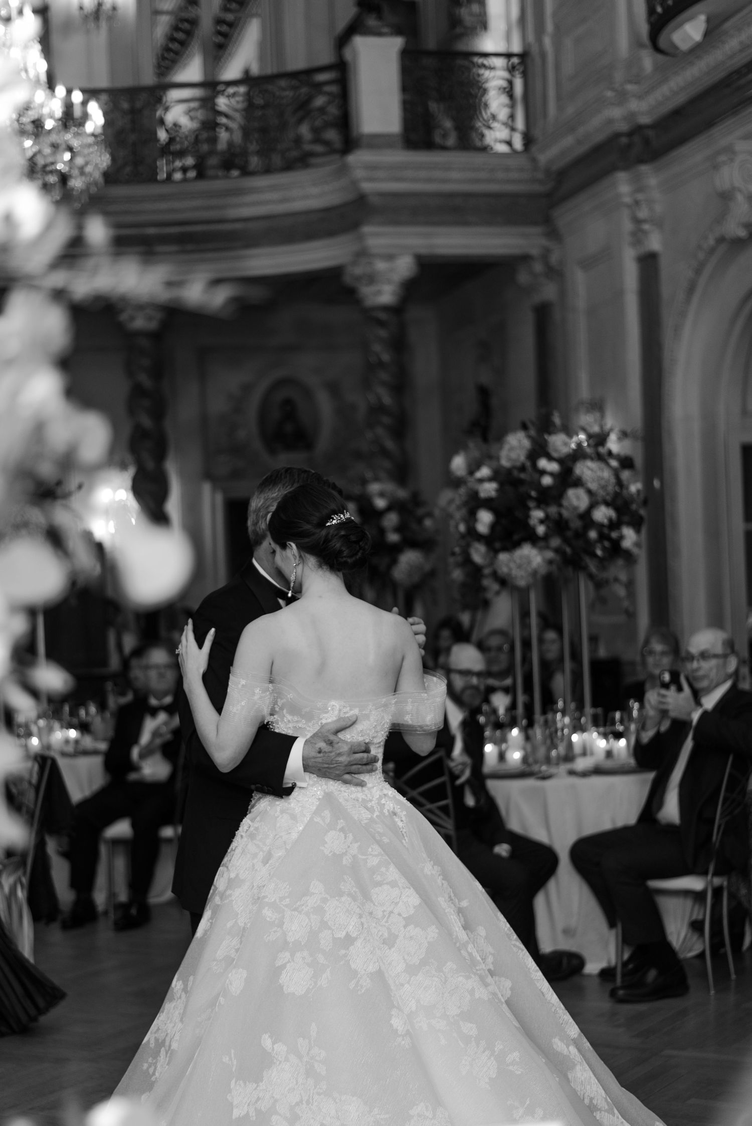 Elegant ballroom dance scene with bride in embellished white gown at a luxurious wedding reception.