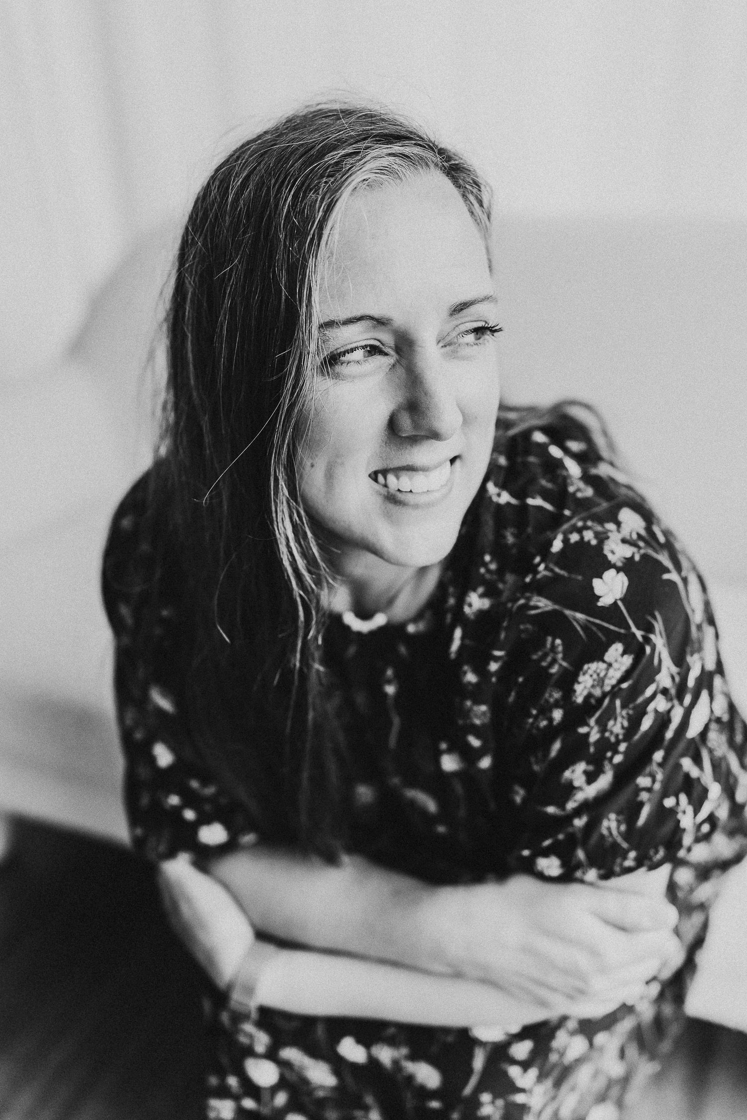 A black and white sequence of four photos showing someone lying down and laughing while wearing a floral print dress.