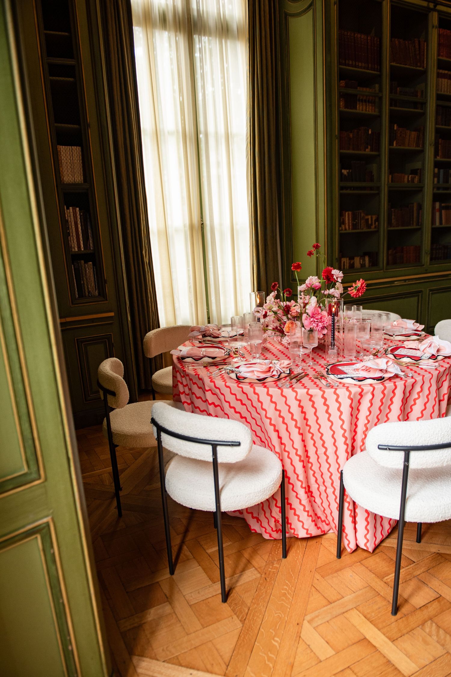 Elegant dining room setup with round tables covered in red and white checkered tablecloths and white chairs.