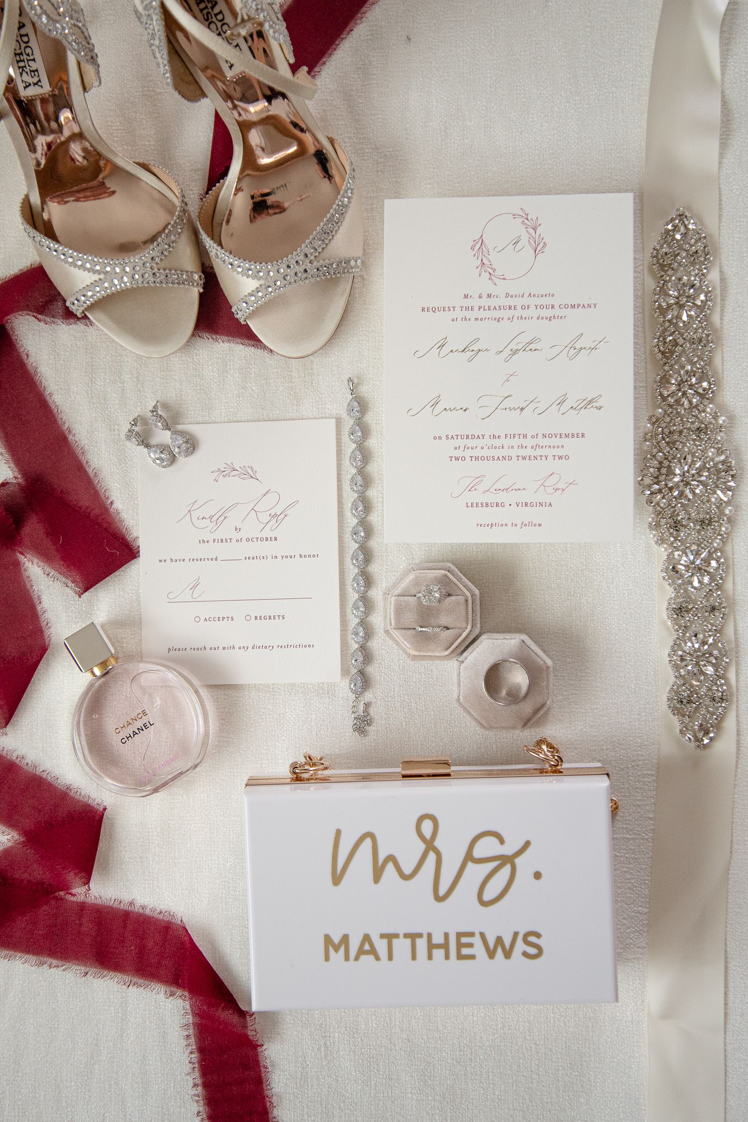 Wedding details flatlay with sparkly shoes, invitations, perfume and Mrs. clutch purse.