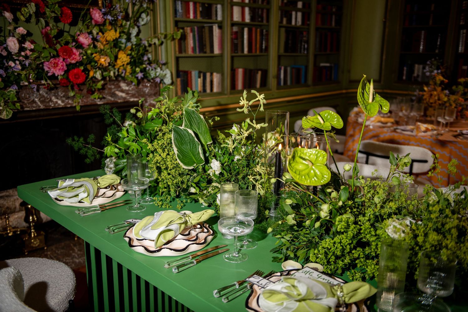 Elegant outdoor dining setup with green accents, white place settings, and lush garden surroundings in evening light.