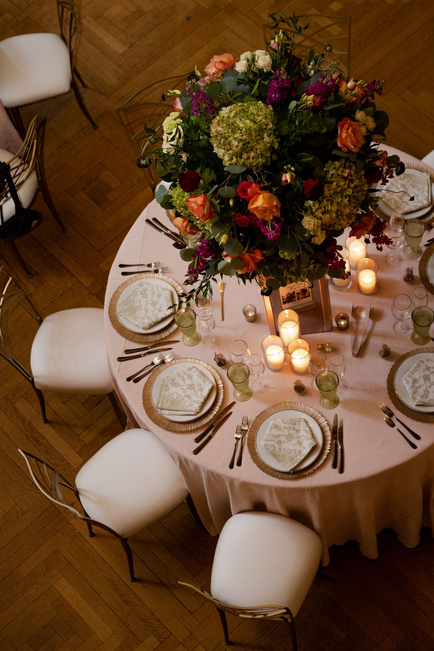 Overhead view of round reception table with lush floral centerpiece and elegant place settings.