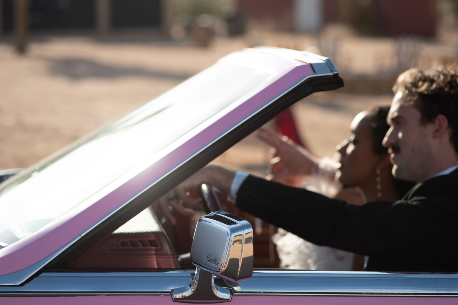 Young people enjoying a drive in a classic convertible car with the top down on a sunny day.