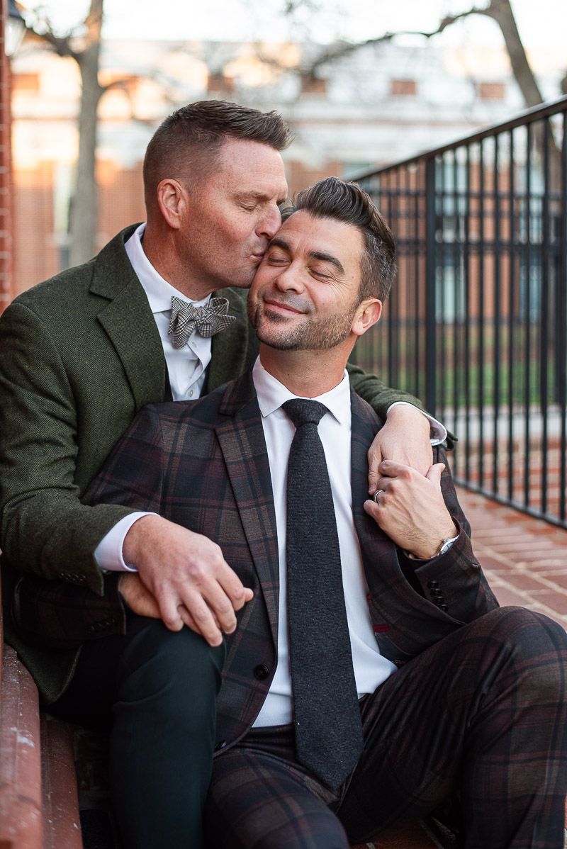 A couple in formal attire share an intimate moment while sitting together outdoors.