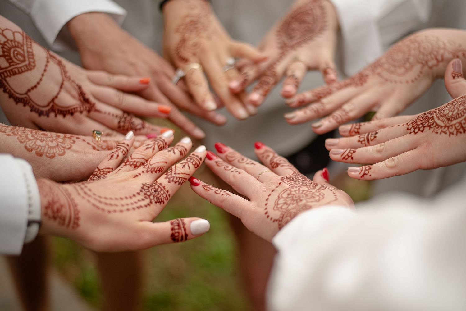Close up of hands with intricate henna designs displayed in a circle.