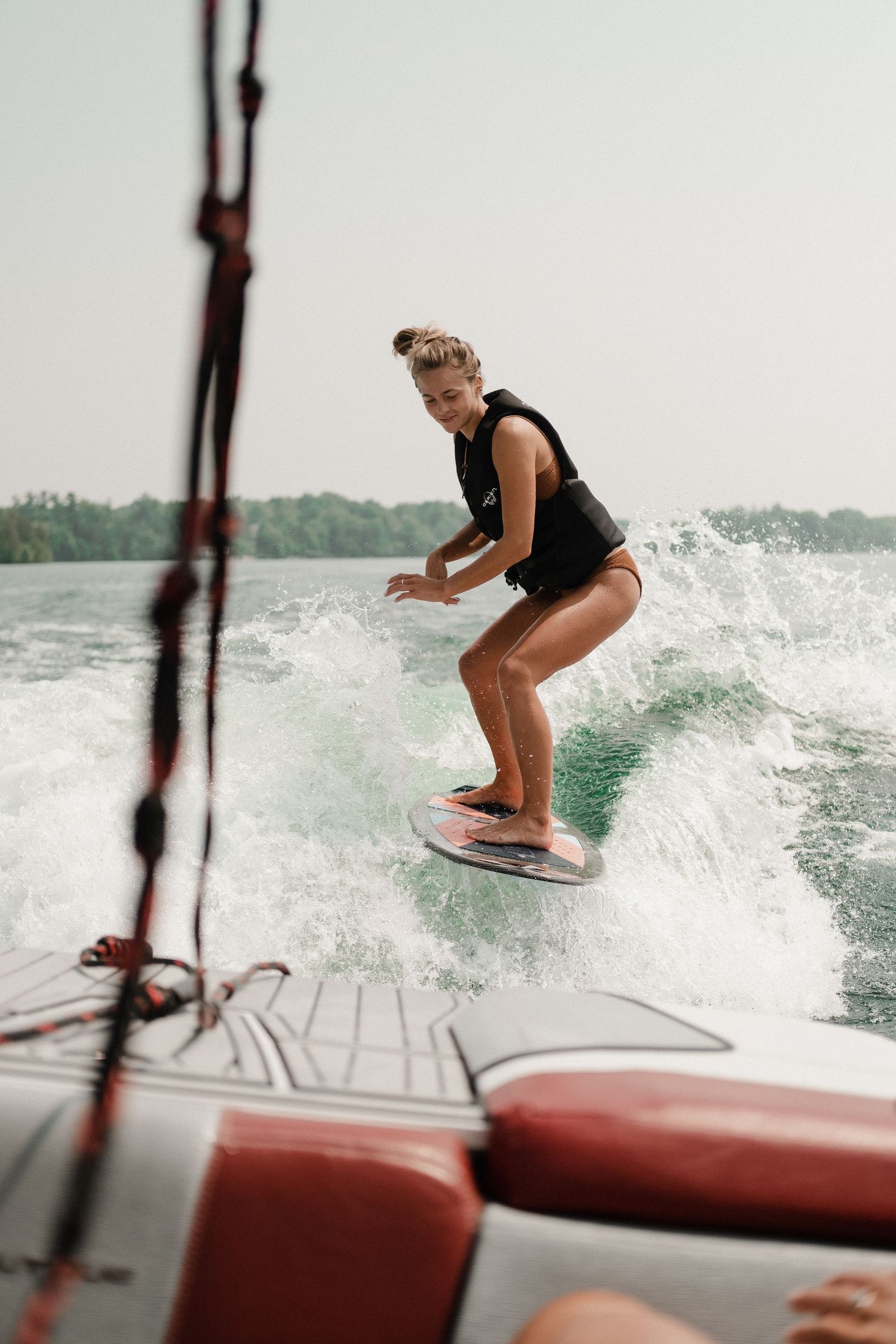 A person wakeboarding behind a boat, creating waves on the water.