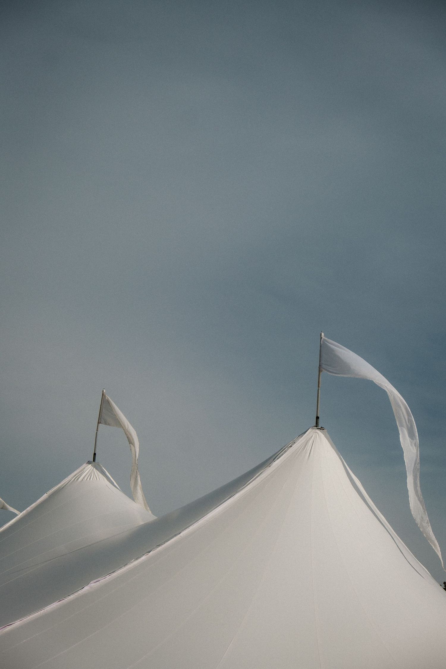 White tent peaks against a moody gray sky creating geometric shapes.