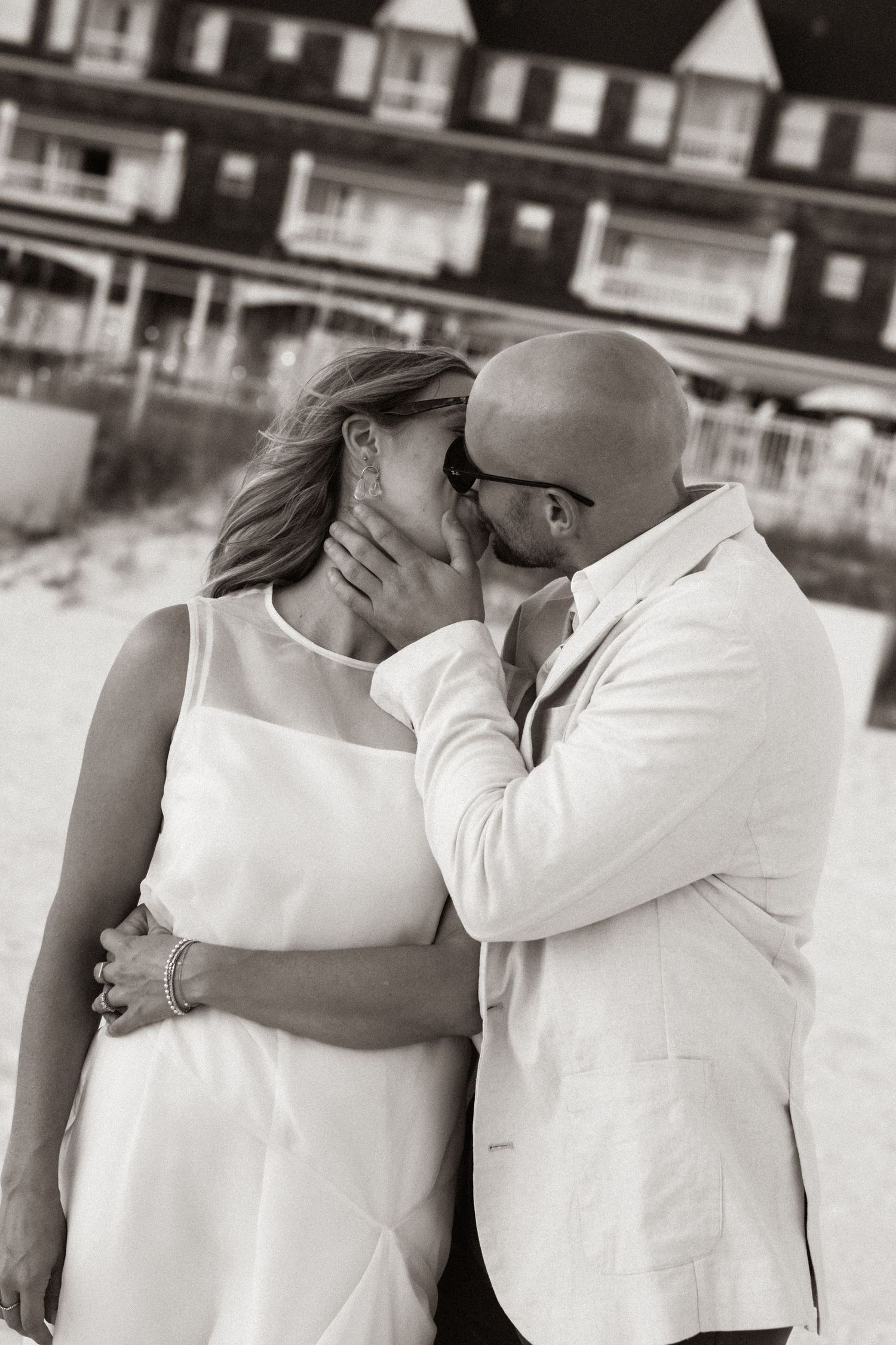 Black and white photo series showing a romantic couple in white clothing embracing and kissing in multiple candid moments.
