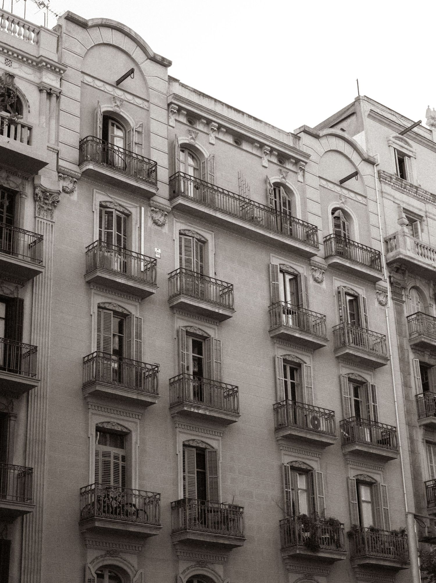 Historic apartment building facade with ornate balconies and tall windows in black and white architectural style.