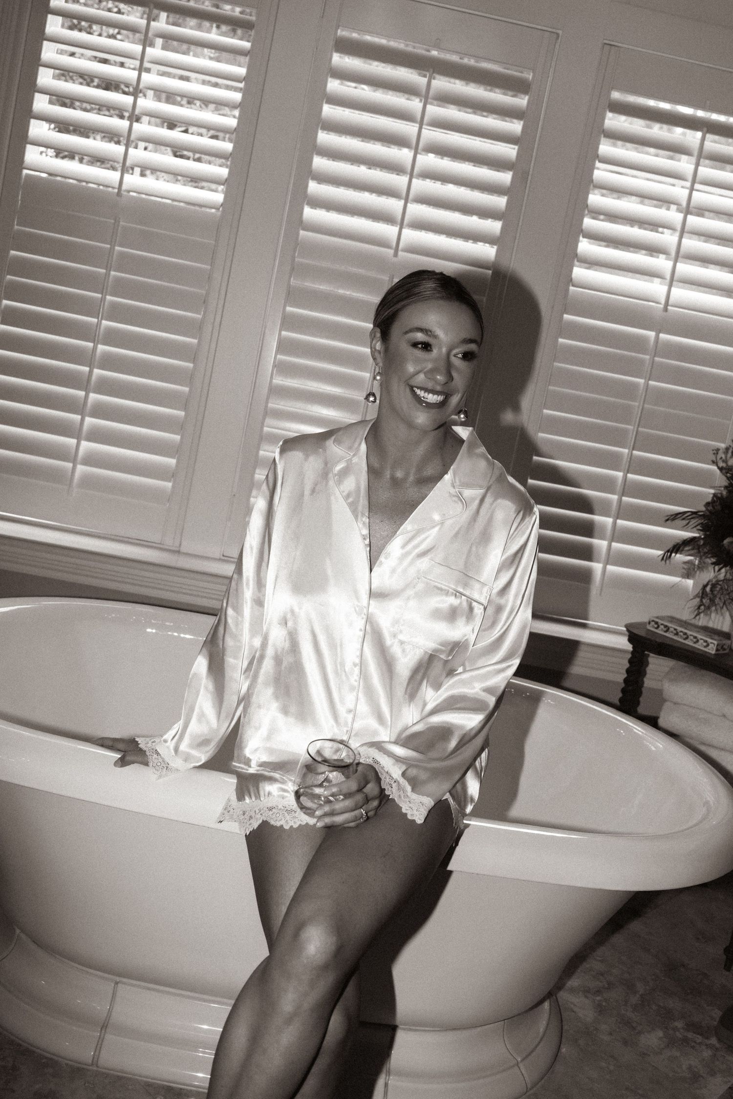 Black and white photo series showing someone in a white silk robe sitting and posing on a bathtub.