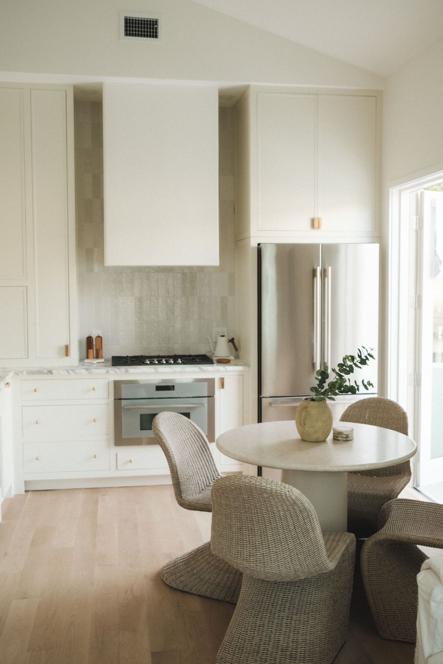Minimalist open concept kitchen and dining area with neutral tones and curved furniture.