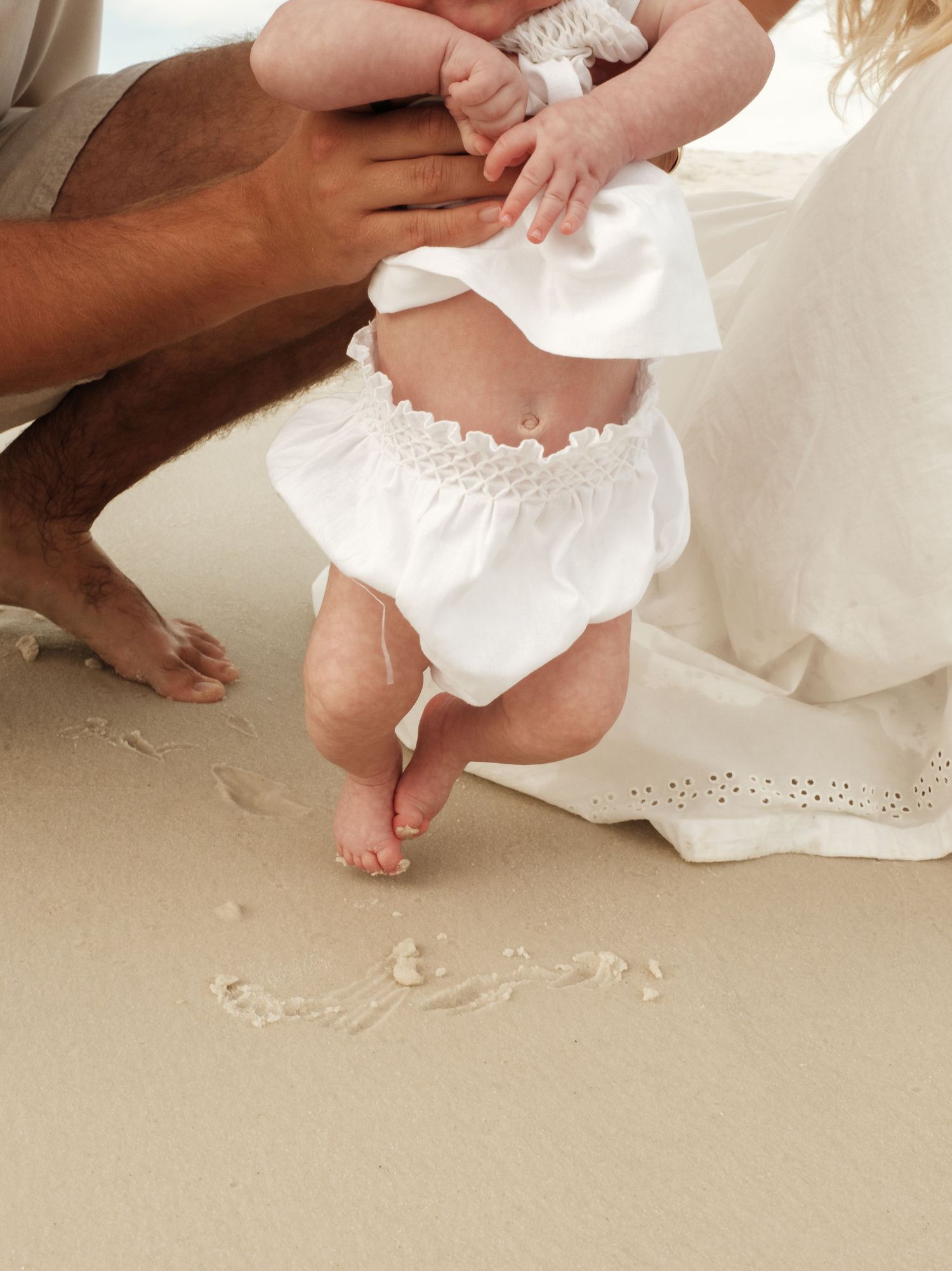 Close-up of tiny baby feet being gently held against white fabric.