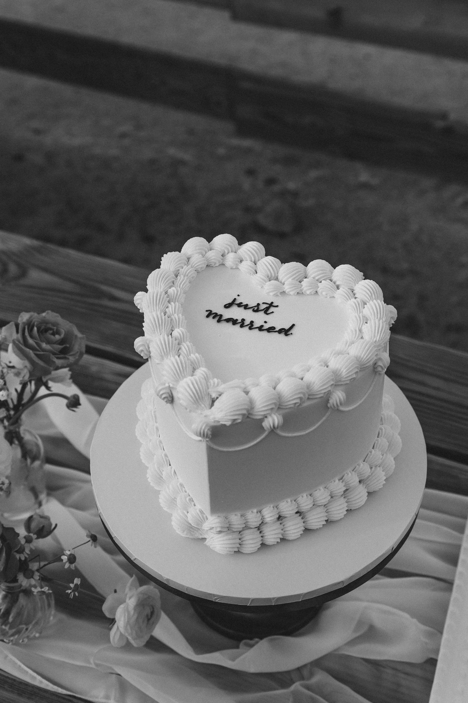A white heart-shaped wedding cake with delicate piped decorations and 