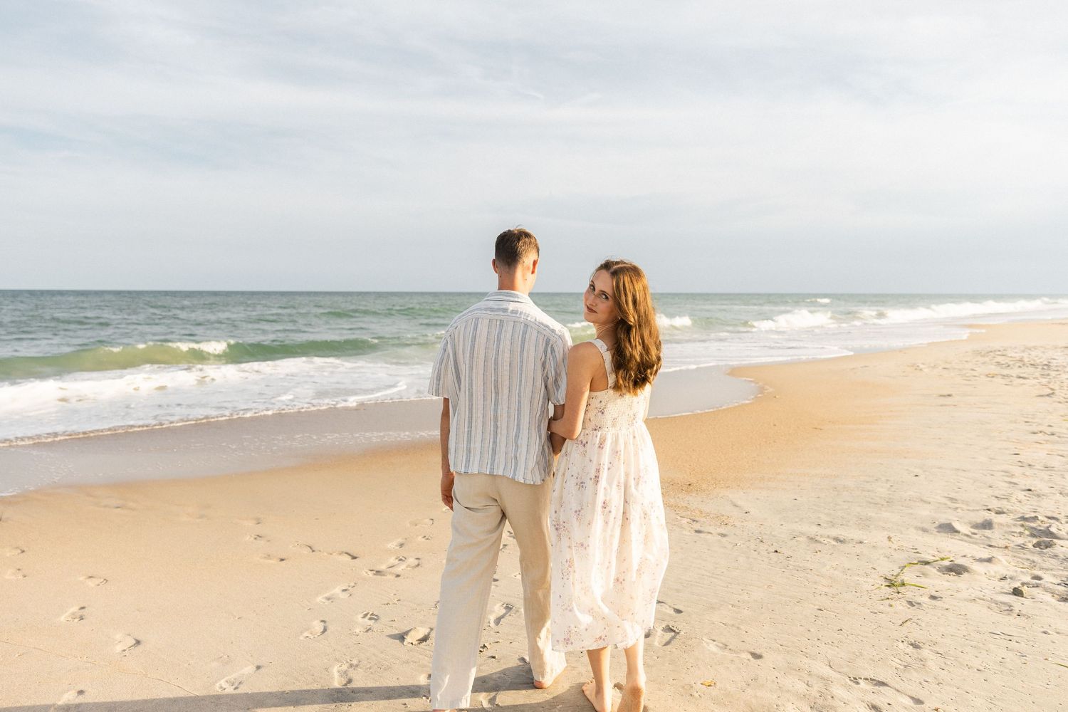 couple walking together on North Carolina beach during their couples photoshoot with Steffanie McCauley Photography
