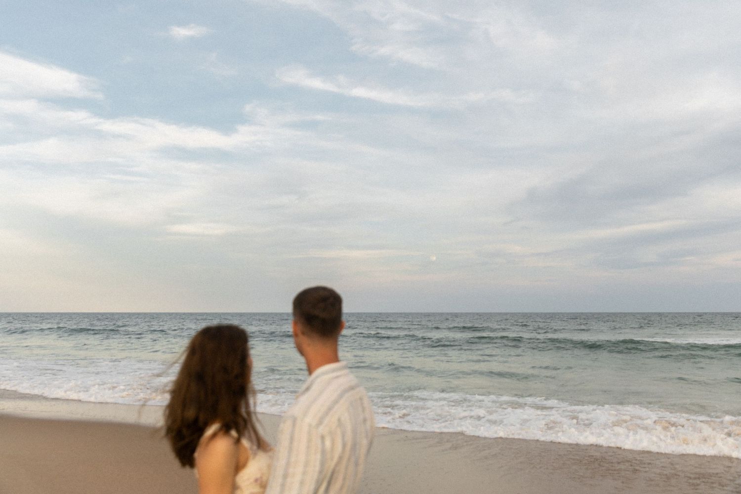 Couple standing by the ocean after sunset on the North Carolina coast
