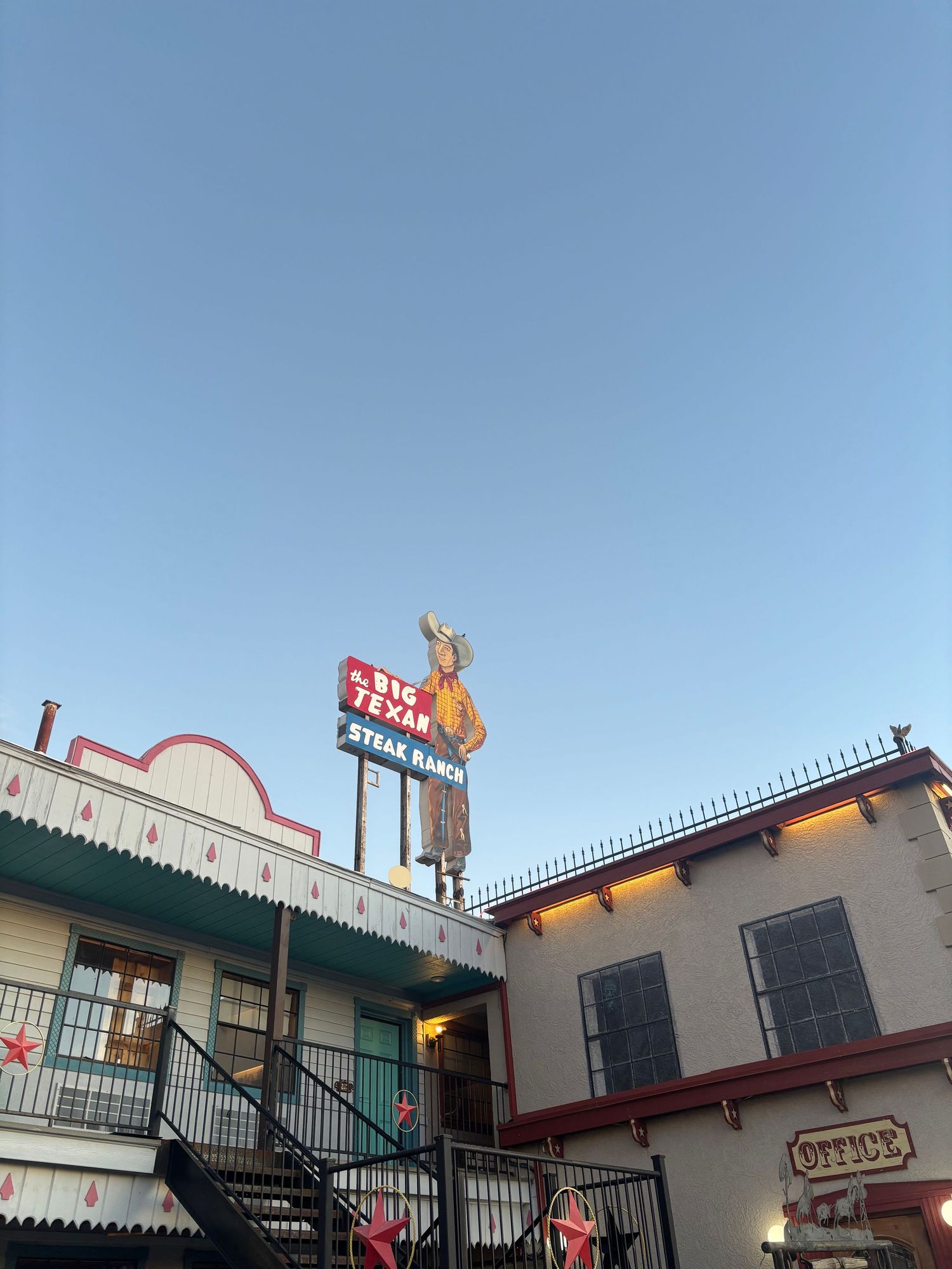 Big Texan Steak Ranch restaurant exterior with iconic cowboy sign and Western-style building at dusk in Amarillo, TX.