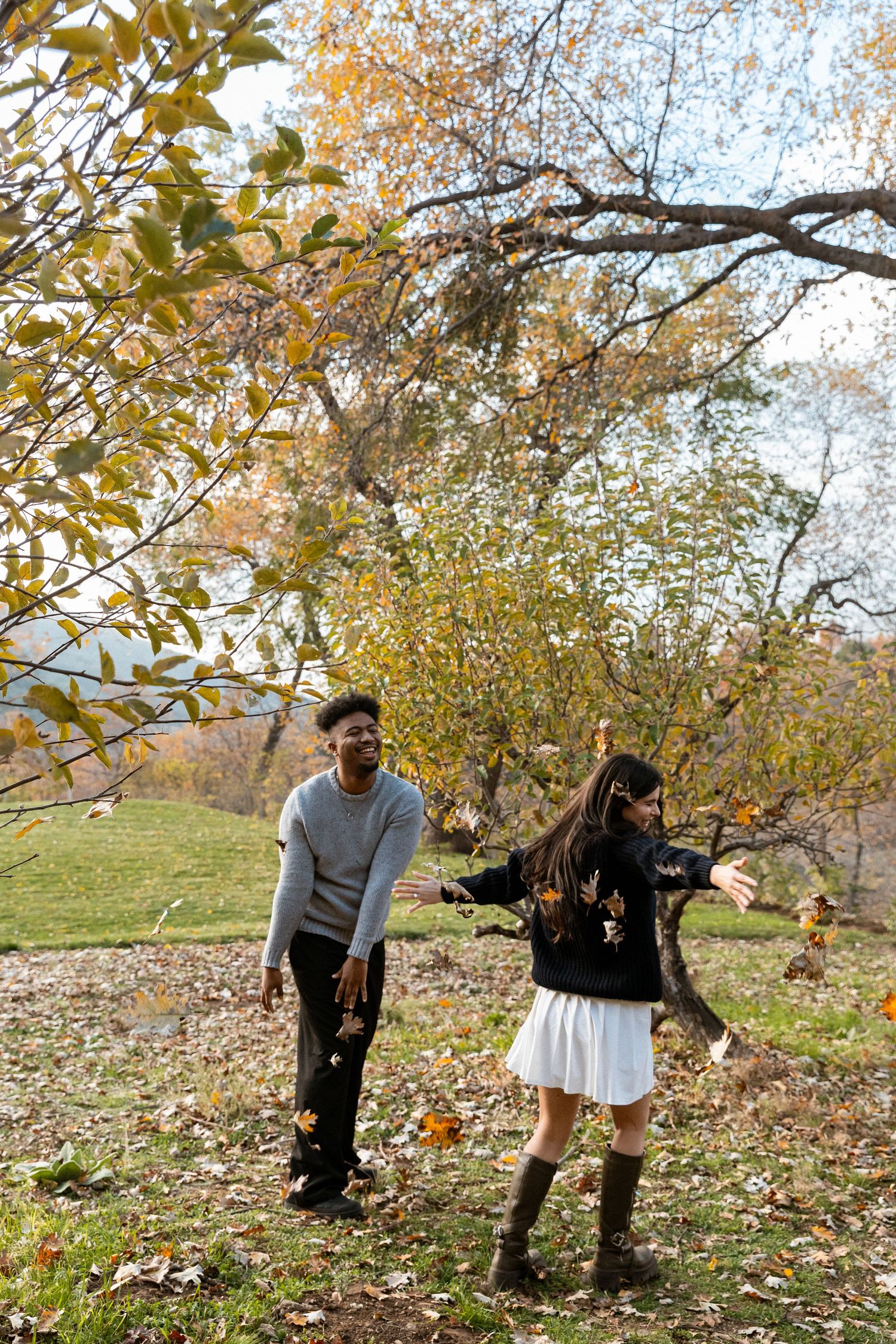 A couple playfully throws autumn leaves in the air while enjoying a fall day in a local Jacksonville North Carolina park
