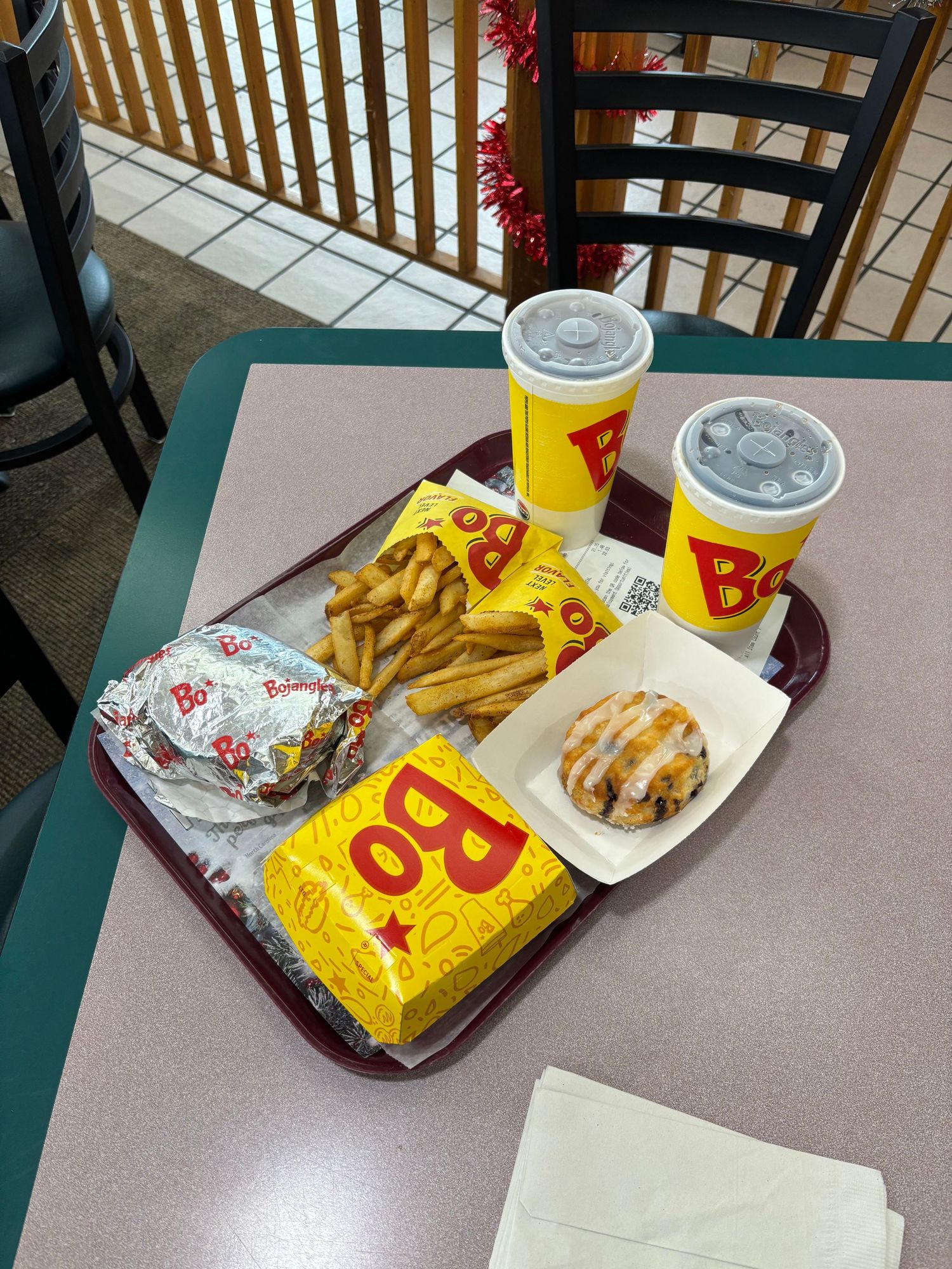 Bojangles fast food meal on a tray with fries, two drinks, a wrapped burger, and a glazed biscuit sandwich.