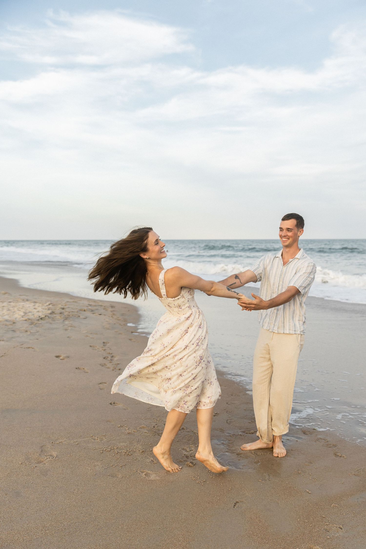 Candid photo of couple spinning on the beach during their engagement photos on north topsail beach