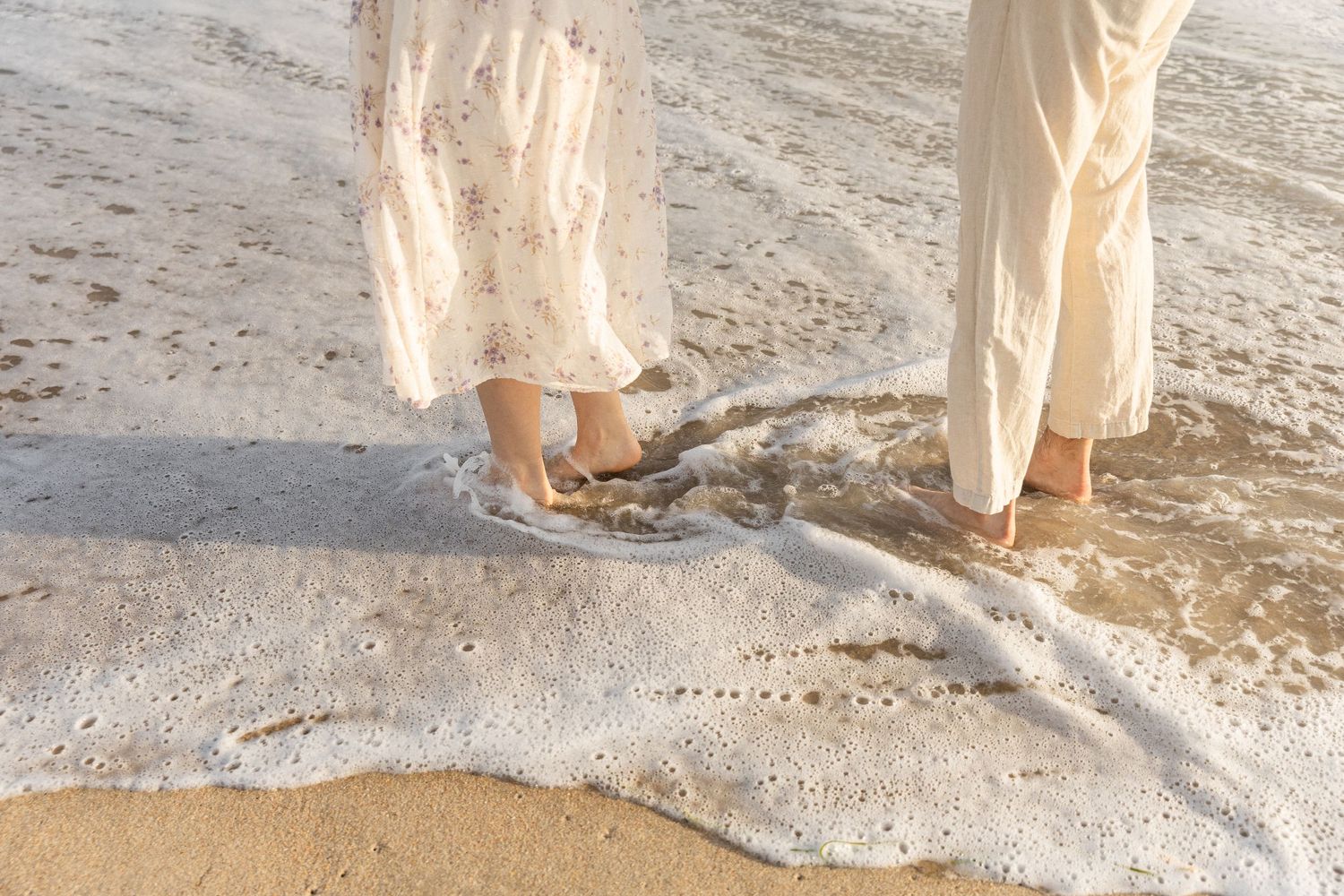 detail photo go couples feet being splashed by the ocean