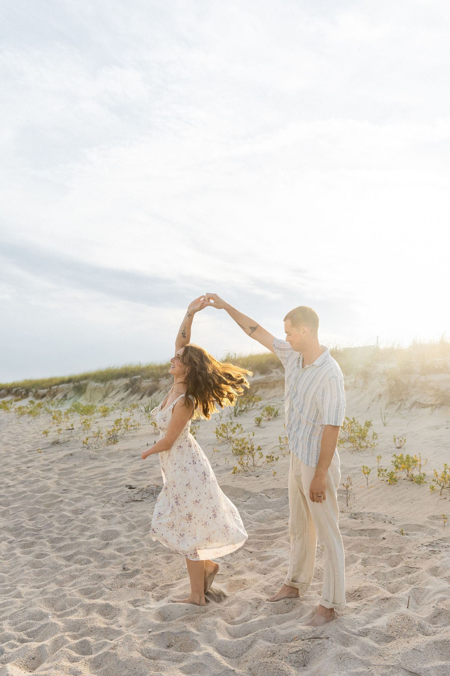 couple daning on beach during golden hour with the sand dunes in the background