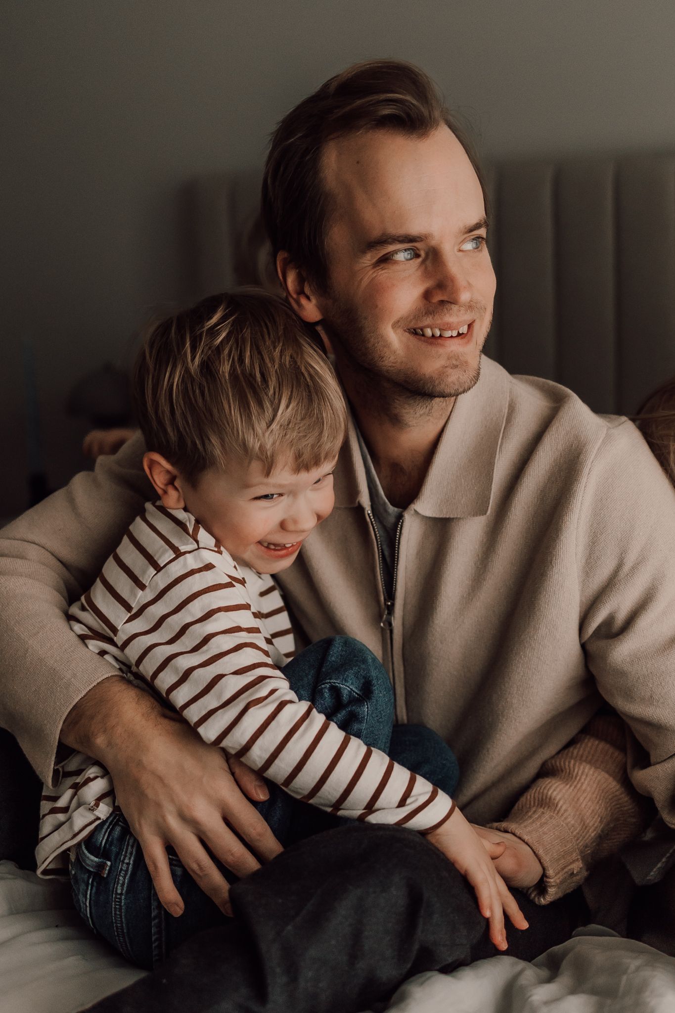 Pappa och son blir fotograferade inomhus i vackert ljus.