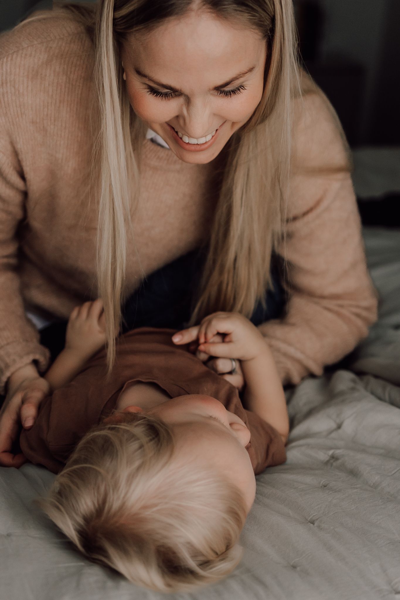 Mamma och son blir fotograferade hemma i vackert ljus.