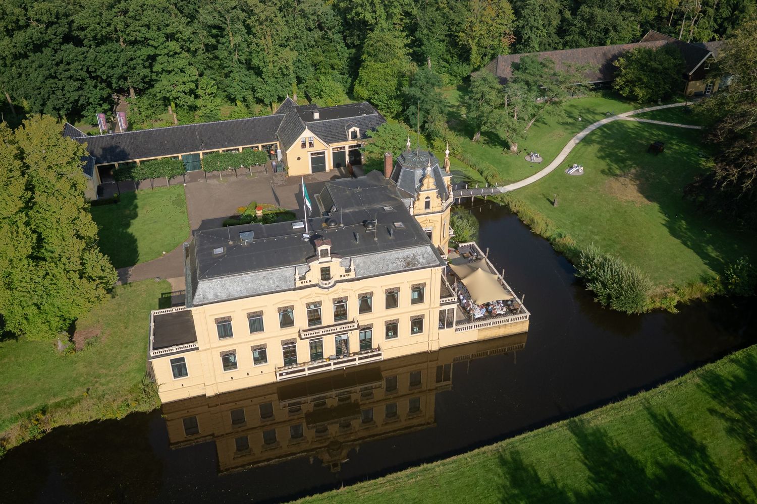 Klassieke gele borg Nienoord in Leek, trouwlocatie vanuit de lucht op een zonnige dag tijdens een bruiloft.