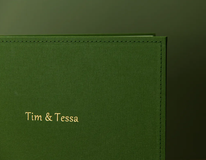 Green linen photo album with gold foil personalized text reading Tim & Tessa, elegant custom wedding keepsake.