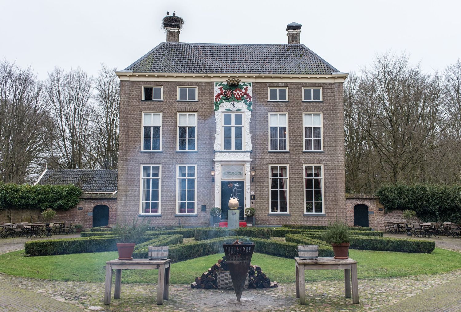 Historic Dutch manor house with formal garden featuring ornamental fountain and symmetrical hedges.