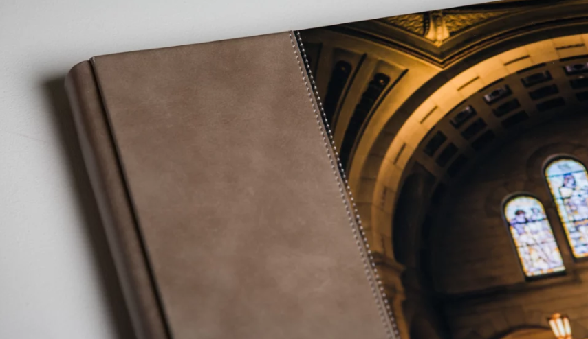 Spiral-bound photo book with brown leather cover displaying a church interior with stained glass windows and ornate architecture.