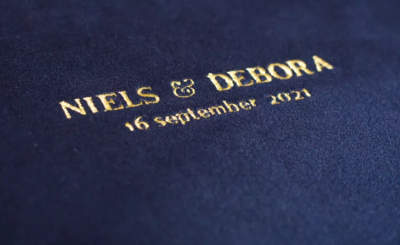 Gold foil embossed wedding album cover reading Niels & Debora 16 September 2021 on navy blue.