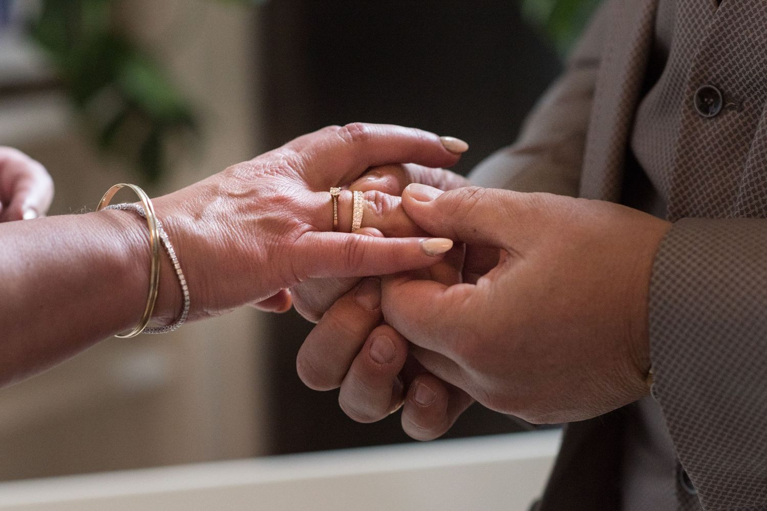 Close-up of two people exchanging wedding rings during a marriage ceremony, symbolizing love and commitment.