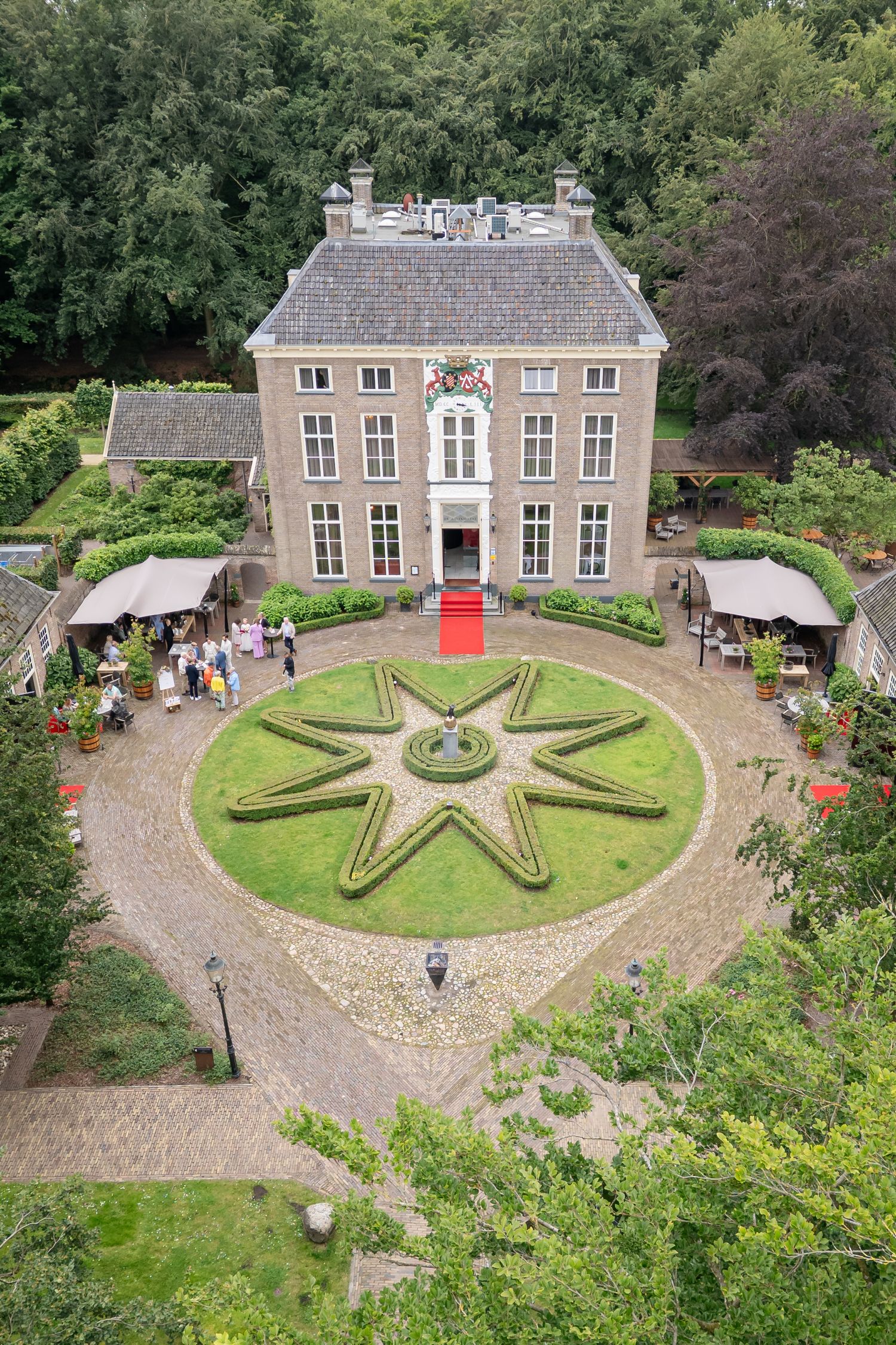 Dronefoto van het historische landhuis De Havixhorst, hier in gebruik als trouwlocatie. De rode loper ligt uit en links bruiloftsgasten