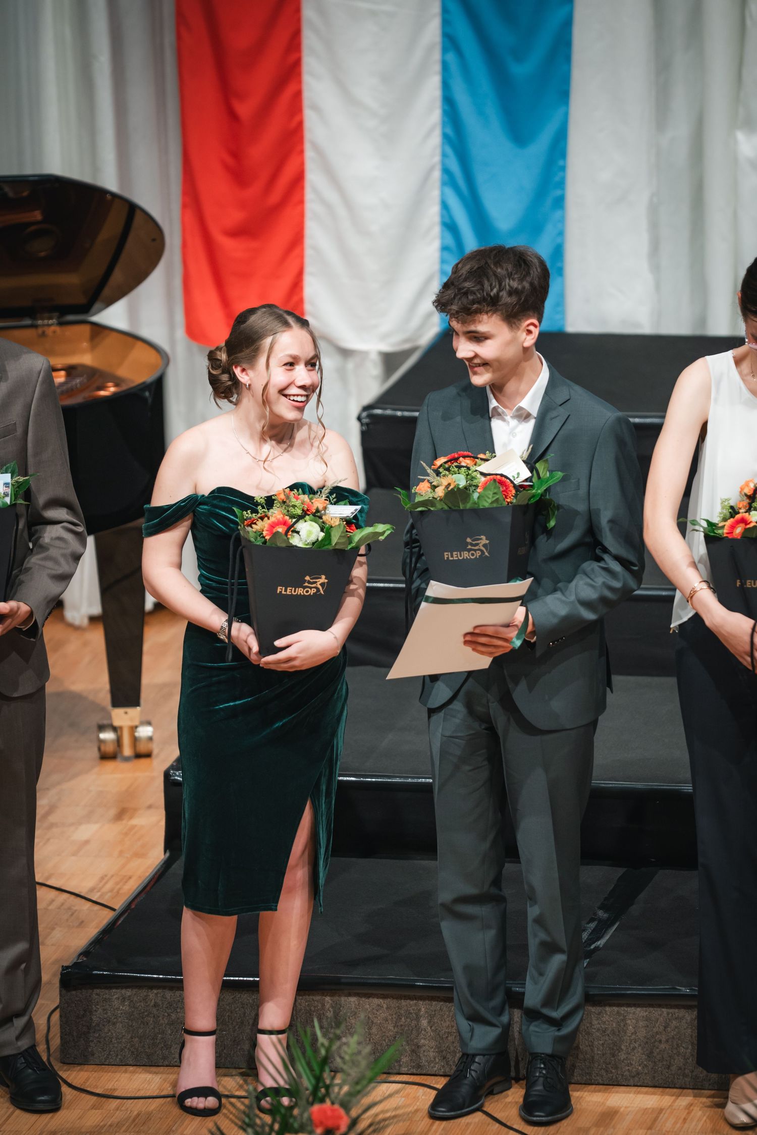Absolvent:innen erhalten Blumen.