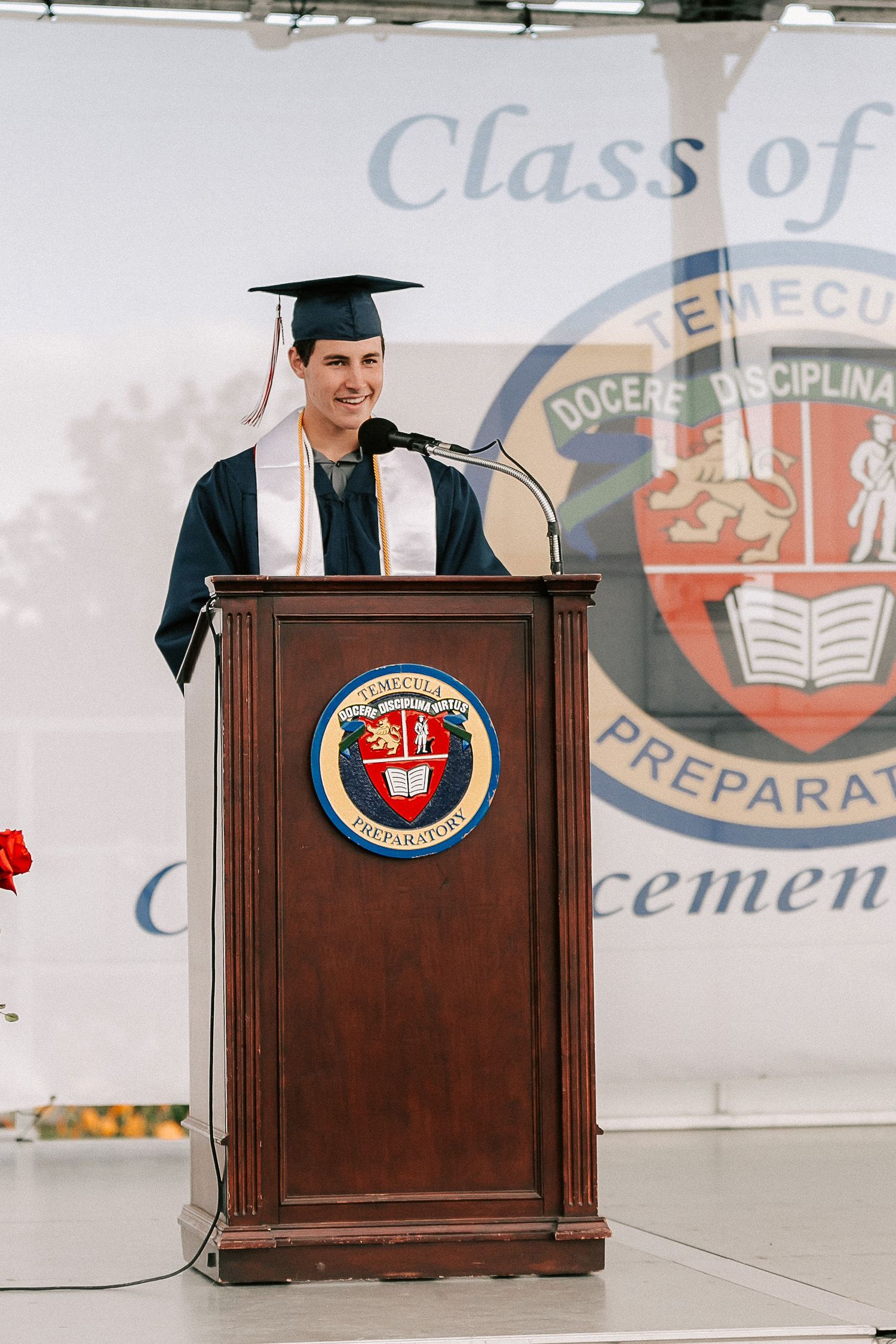 Graduate in cap and gown delivers commencement speech at Temecula Preparatory School Class graduation ceremony.