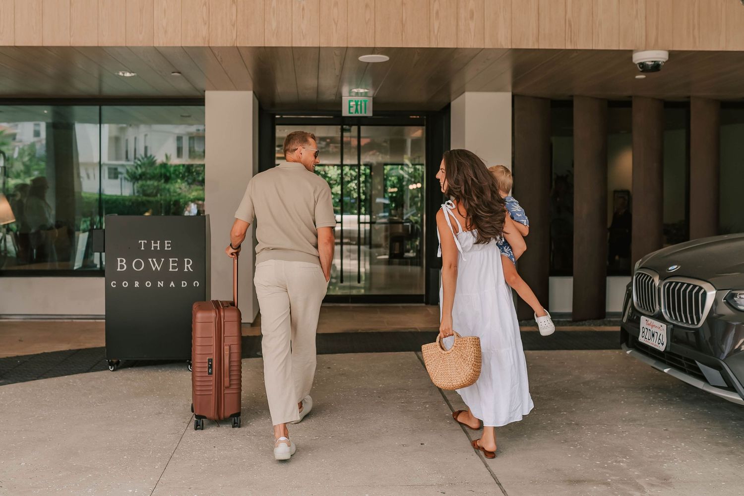 Family arriving at The Bower Savannah hotel entrance with luggage and a BMW parked outside.