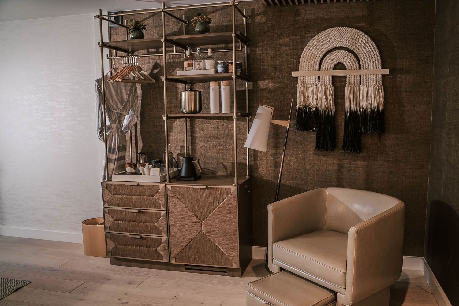 Bohemian living room with wooden shelving unit, leather armchair, and macrame wall hanging decor.