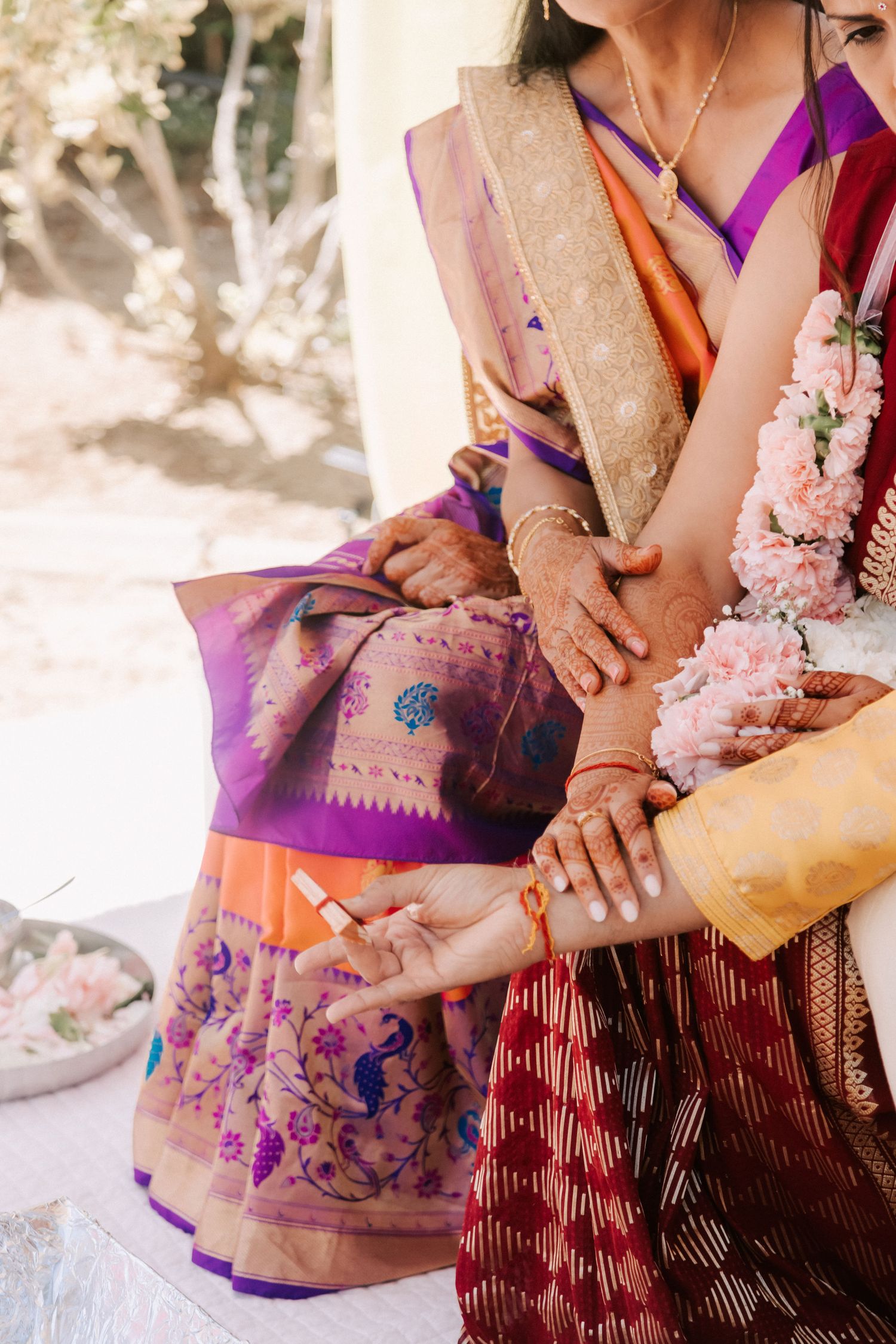 Close-up of hands adorned with henna and gold bangles during an Indian wedding ritual ceremony.