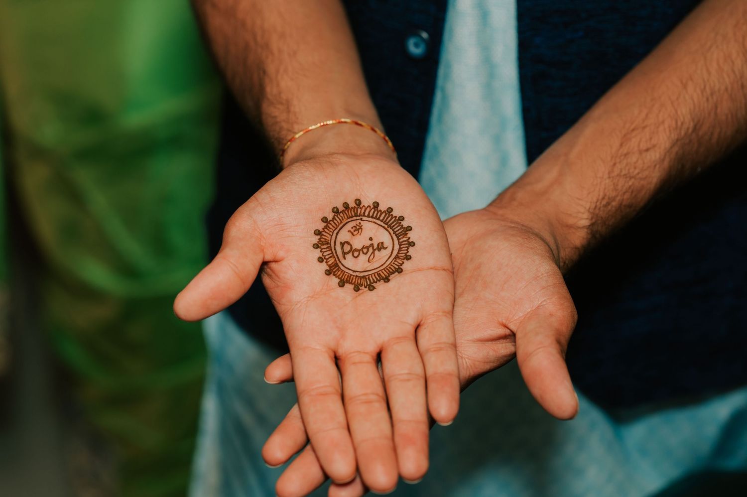 Groom displays intricate mehndi henna design with bride's name on his palm at Indian wedding.